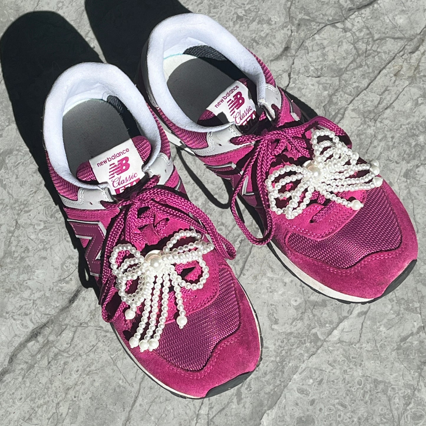 une paire de baskets roses avec des bijoux de chaussures en perles blanches