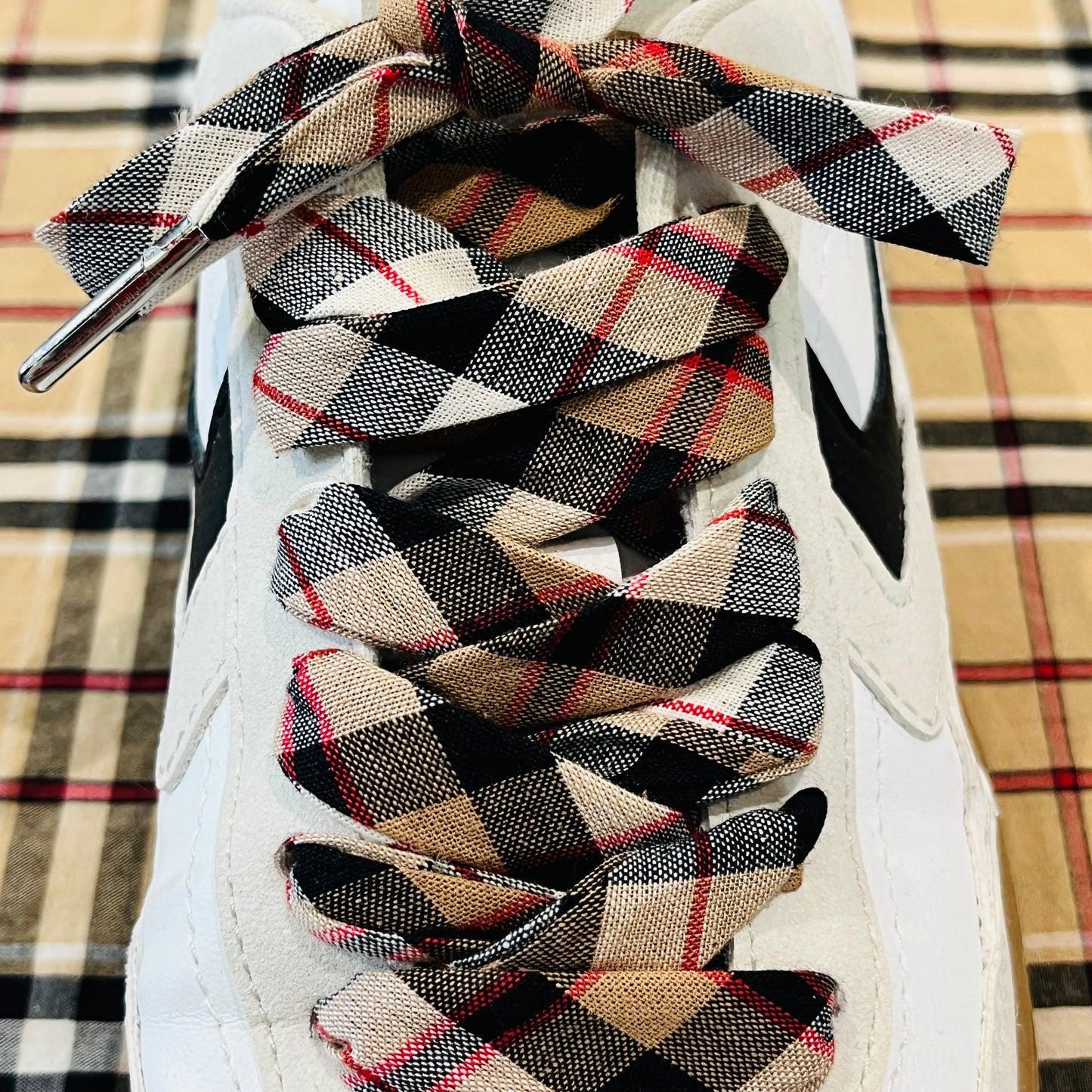 lacets tartan à carreaux beiges et rouges avec des aglets argentés.