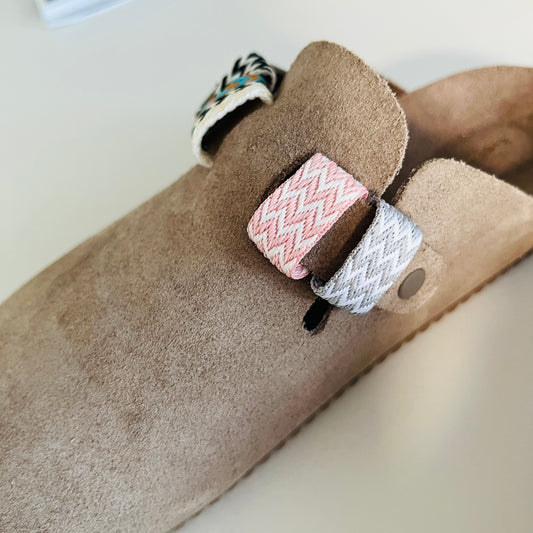 une birkenstock Boston avec une bague rose et blanche, une bague grise en blanche en tissage brésilien