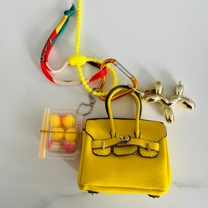 mini sac rigide jaune avec mousqueton coeur jaune, mini chien doré et mini boite à sushis et mini foulard