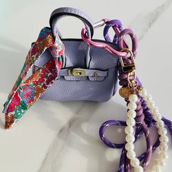 mini sac de couleur parme avec breloques et mousqueton coeur mauve et mini foulard liberty fleuri