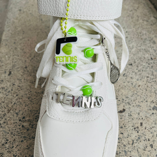 une basket avec un Pack BIJOUX charms raquettes de Tennis fixées sur les lacets blancs et rubans blancs avec balles de tennis et lettres tennis argentées