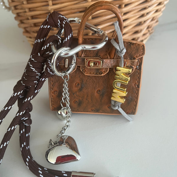 mini sac marron imitation autruche accroché sur un sac en paille avec mousqueton coeur argenté et boot de bateau couleur chocolat