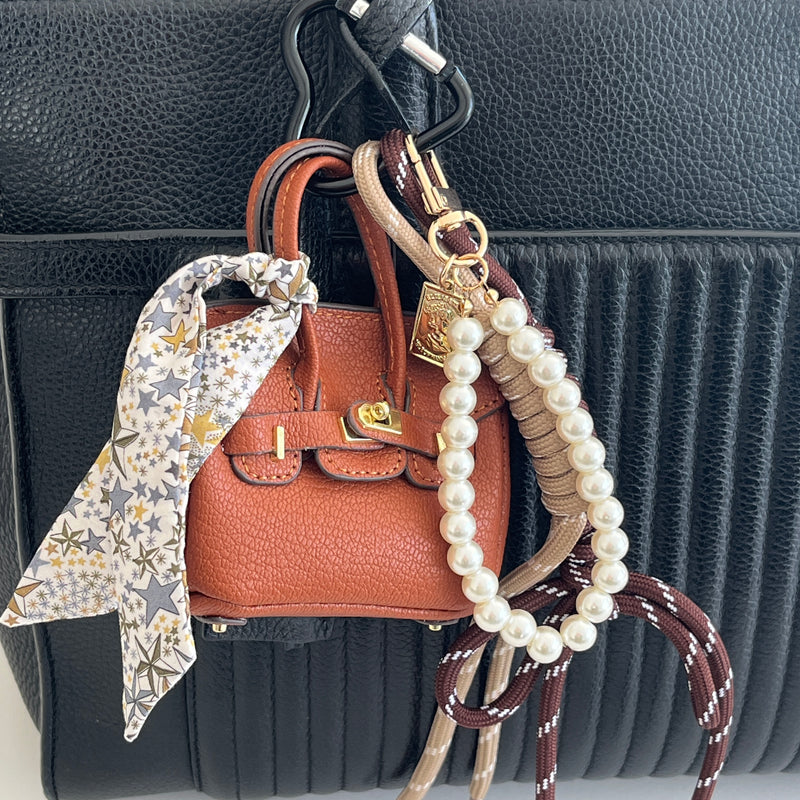 mini sac marron accroché à un sac noir avec mousqueton coeur noir et breloques et mini foulard liberty avec étoiles grises et ocres
